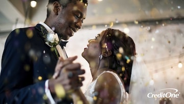 A bride and groom dance at their wedding with confetti falling around them. The newlyweds considered the pros and cons of using a credit card when planning their dream wedding.